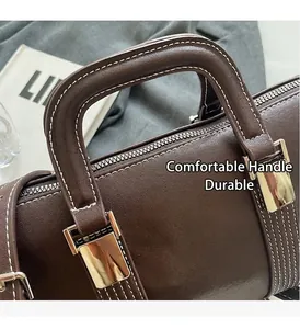 Détail du sac à main en cuir marron foncé avec coutures contrastées et accents argentés