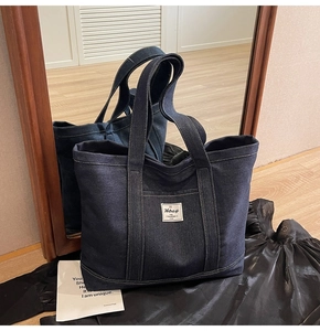 Macro detail of dark indigo denim tote bag with side pocket and white woven label