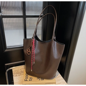 Détail du grand sac cabas en cuir marron foncé avec charme tressé et design seau