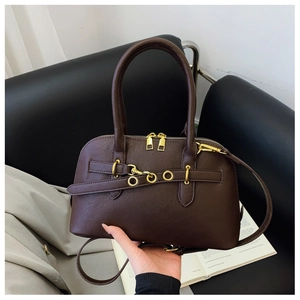 Detail of dark brown retro shell bag with gold hardware and stylish metal eyelet belt