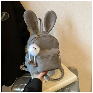 Gros plan d'un mini sac à dos en velours gris avec oreilles de lapin et pendentif peluche