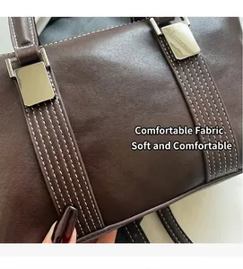 Détail d'un sac à main en cuir marron foncé avec coutures blanches et boucles argentées