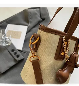 Détail du sac seau en toile avec garniture en cuir marron et boucles dorées chic