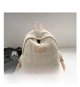 Close-up of quilted beige cotton backpack with minimalist leather tag and zipper detail