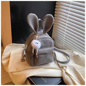 Détail du sac à dos gris en daim avec oreilles de lapin, zips dorés et pompon blanc