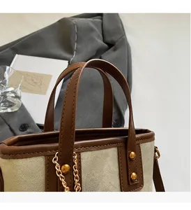 Détail du sac cabas en toile beige avec bordure en cuir marron et clous dorés