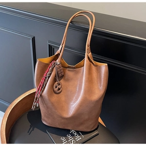 Détail du grand sac cabas en cuir marron foncé avec ses breloques biscuit et chocolat