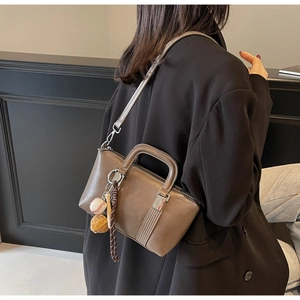Gros plan d'un sac à main marron en similicuir avec charme baseball et bandoulière