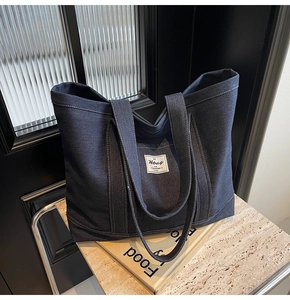 Detail of deep blue denim tote bag with white contrast stitching and branding label
