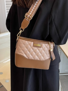 Chic beige and brown quilted crossbody bag with wide jacquard strap on a black blazer