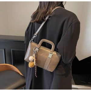 Détail du sac à main en cuir marron foncé avec boucles argentées et charme de sac sport