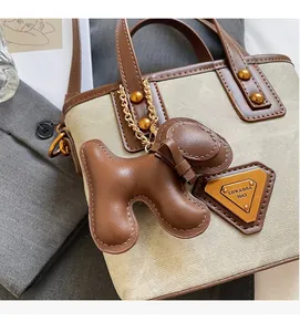 Détail du sac seau en toile avec finitions en cuir et breloque chien dorée décorative