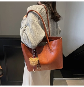 Detail of amber brown leather tote bag with vintage texture and cute plush bear charm
