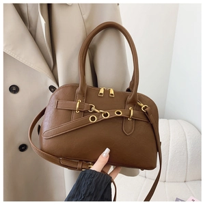 Detail of brown faux leather handbag with gold buckles, dual zippers and textured finish