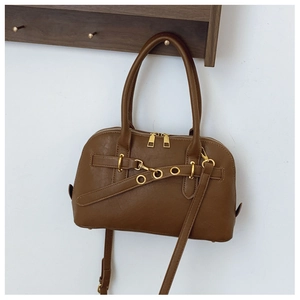 Caramel brown PU leather shell bag hanging on a wooden wall rack with gold hardware