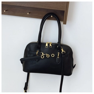Detail of black faux leather handbag with gold metal rings and dual zipper closure