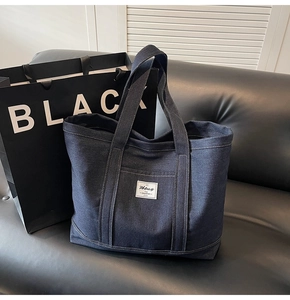 Detailed view of dark blue denim tote bag texture with minimalist white label and handles