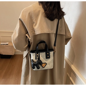 Sac seau chic en toile grise avec garniture en cuir noir et breloque sur mannequin
