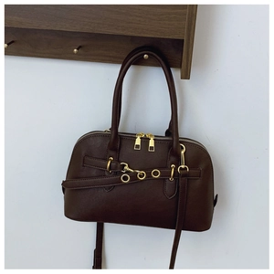 Detail view of coffee brown leather boston bag with gold hardware and removable shoulder strap