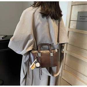 Détail du sac Boston en cuir marron foncé avec pendentifs baseball en décor de bureau