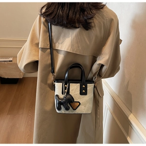 Détail du sac seau en toile avec finitions en cuir noir et breloque chiot chic