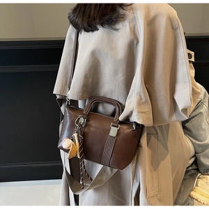 Détail d'un sac à main vintage en cuir marron avec porte-clés baseball et bandoulière
