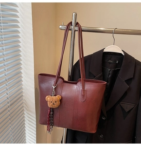 Detail of burgundy large tote bag with cute bear charm and tassel on hanger