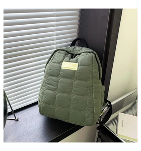 Nahaufnahme des salbeigrünen gesteppten Rucksacks mit gepolsterter Textur auf Holzsims