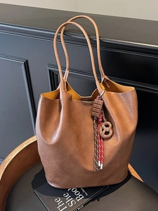 Sac seau vintage marron en cuir avec breloques créatives sur une chaise élégante