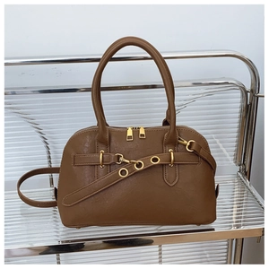Close-up of brown faux leather handbag with gold zipper, rings, and detachable strap