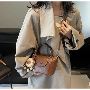 Brown vintage leather crossbody bag worn by model with a white plush sheep charm
