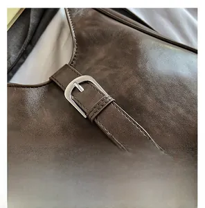 Vue détaillée du cuir synthétique marron foncé et de la boucle argentée sur le sac