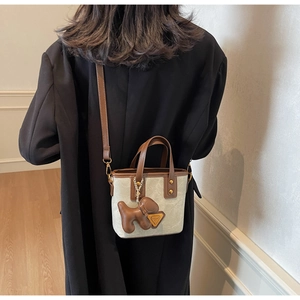 Sac seau minimaliste crème avec garniture en cuir marron porté en bandoulière
