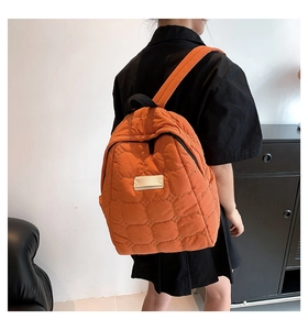 Rückansicht des orangefarbenen gesteppten wasserdichten Rucksacks an einem weiblichen Model