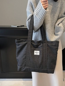 Large dark grey denim tote bag with minimal branding and sturdy shoulder handles