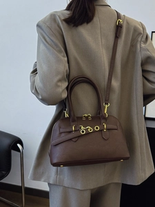 Vintage dark brown shell-shaped crossbody bag with gold hardware ring on beige blazer