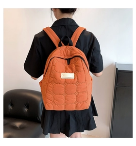 Detail des orangefarbenen Stepprucksacks mit Puffer-Struktur und weißem rechteckigem Label