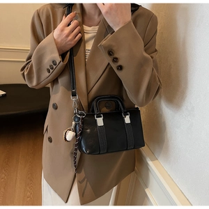Détail du mini sac à main noir avec boucle métallique et breloque de baseball au côté