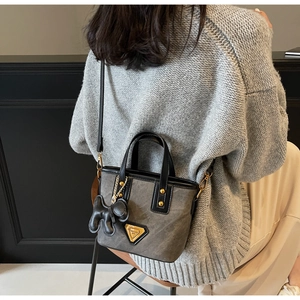 Détails de la texture du tissu gris avec logo en métal doré et breloque chien noir