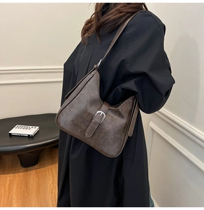Détail d'un sac seau vintage marron montrant la texture du cuir et la boucle argent