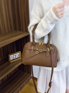 Vintage brown leather crossbody bag with dual zippers and gold hardware in an autumn setting
