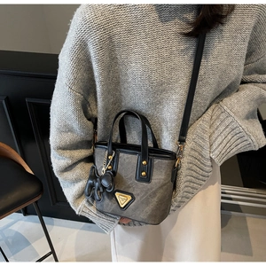 Détail du mini sac seau gris avec finitions dorées et charm animal en cuir noir