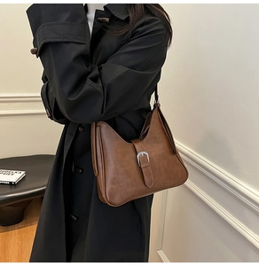 Détail du sac sous le bras rétro marron foncé avec boucle en métal argenté sur cuir mat