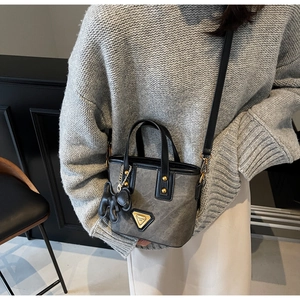 Vue détaillée du sac seau gris vintage avec poignées en cuir noir et plaque métal