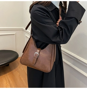 Détail de la boucle en métal réglable et texture cuir marron foncé du sac hobo