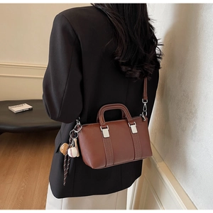 Détail du sac à main en cuir mat marron foncé avec pendentif baseball et boucles argent