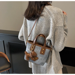 Vue détaillée du sac seau en toile avec garniture cuir et breloque chien sur modèle