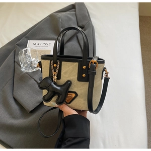 Détail du sac seau en toile avec bordure en cuir noir et breloque chien sur une veste
