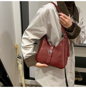 Détail du sac hobo bordeaux vintage avec boucle argentée sur un trench-coat beige