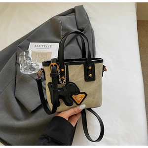 Détail du sac seau en toile et cuir noir avec clous dorés et breloque chien